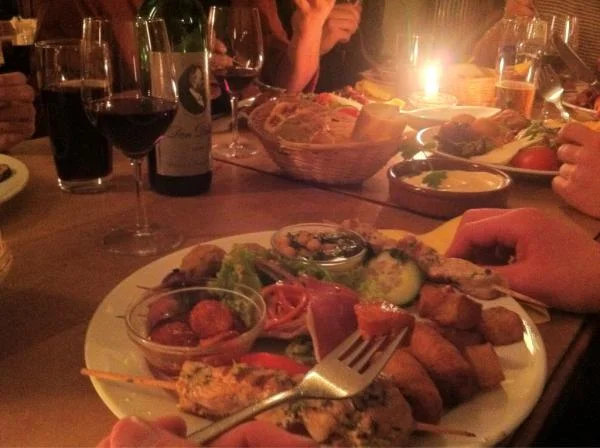Ein festliches Abendessen mit Fleischgerichten, Gemüse, Rotwein und Kerzenbeleuchtung auf einem gedeckten Tisch.