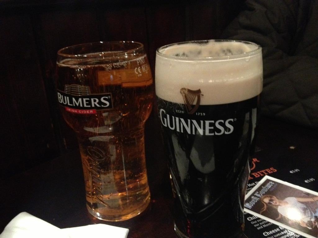 Ein Glas Bulmers Irish Cider und ein Glas Guinness Bier stehen nebeneinander auf einem dunklen Tisch.