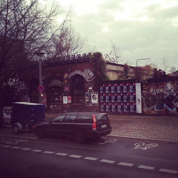 An black Volvo in front of a broken down red brick building