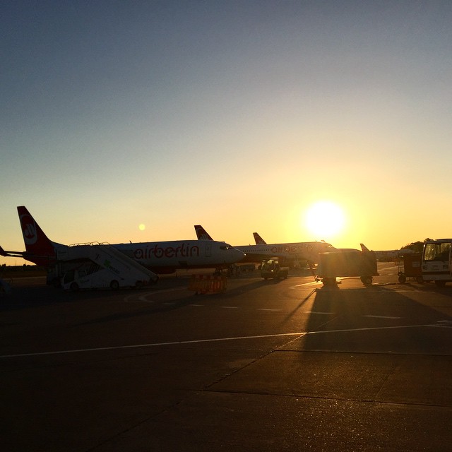 Three small airplanes on a runway during sunrise