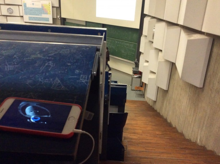 A auditorium, blue folding tables, a white iPhone shows a frame of the tv series "Star Trek Voyager"