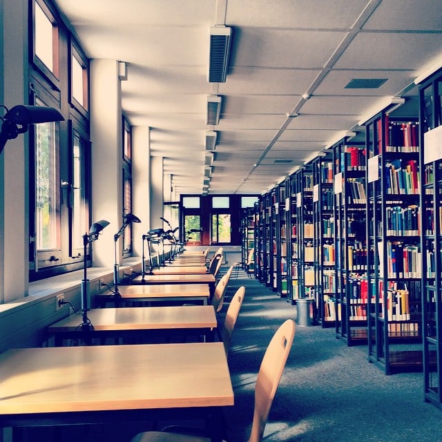 A long row of desks on the left facing windows. A row of bookshelves on the right