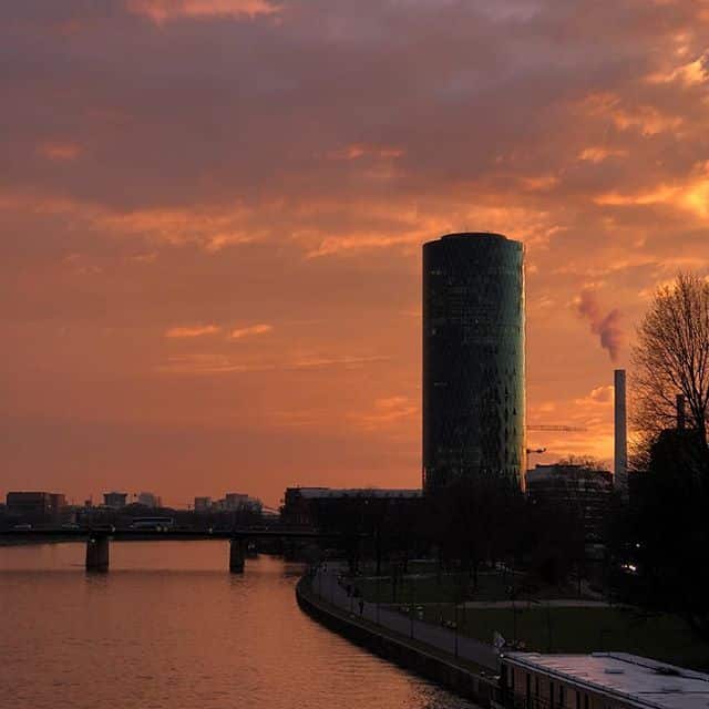 Round high-rise next to a river. Sunset in the background