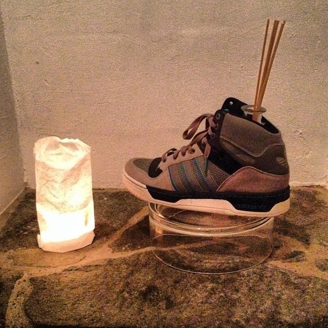 A candle on the left and a sneaker on the right with some room scent poking out