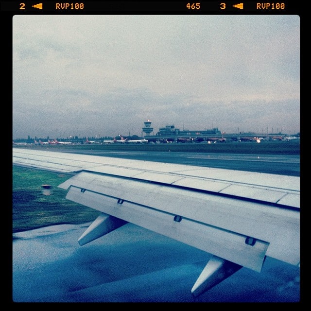 View from inside an airplane while landing. Wing over runway, airport tower in the background