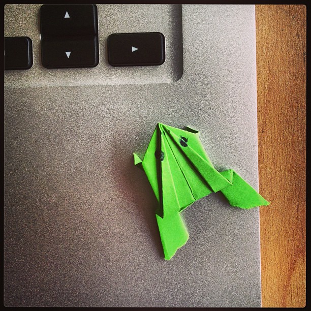 A green paper frog on a silver MacBook