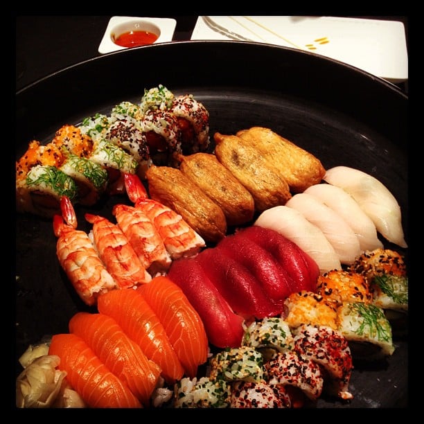 Rows of neatly aligned sushi on a black plate