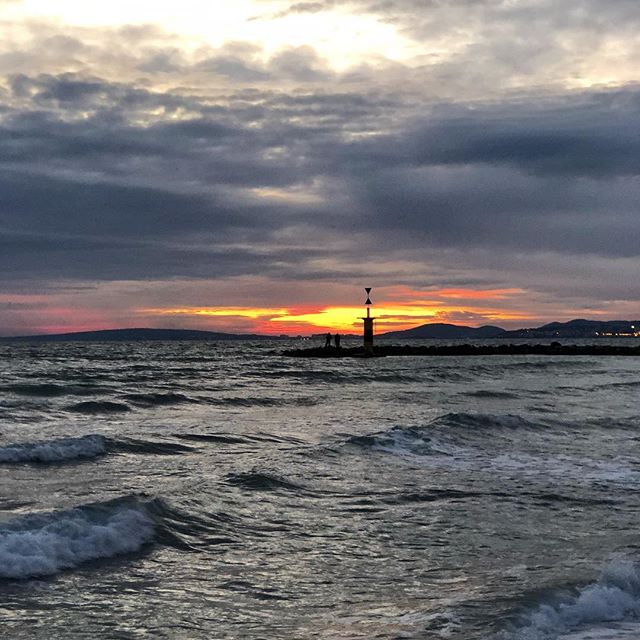 Sunset over a bay. Two fishermen sit together