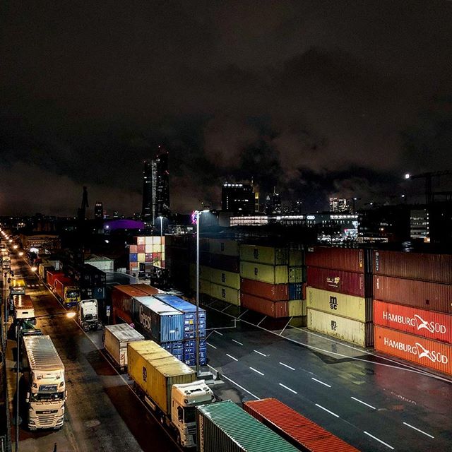 A shipping yard with a bunch of stacked containers