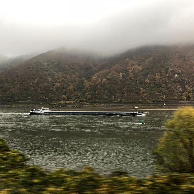 A freighter in the middle of a river with greenery in the fore- and background