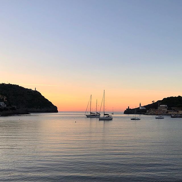 A bay, sunset in the background with three sailboats