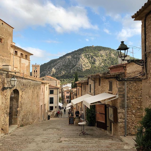 A narrow old street between old sandstone buildings with a mountain range in the background