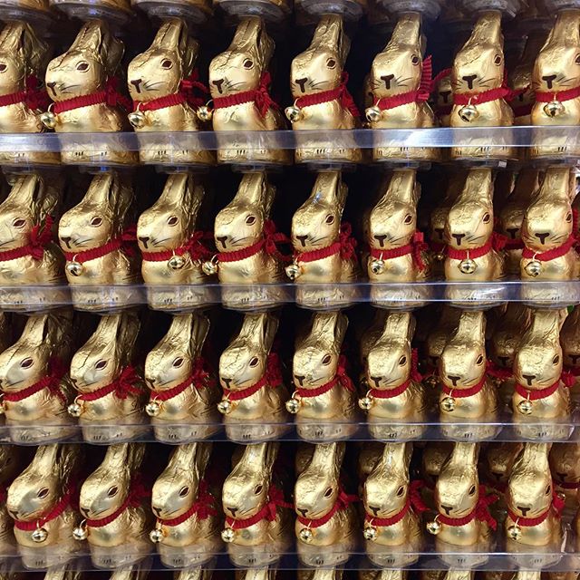 Stacked golden chocolate rabbits each with a red ribbon around the neck