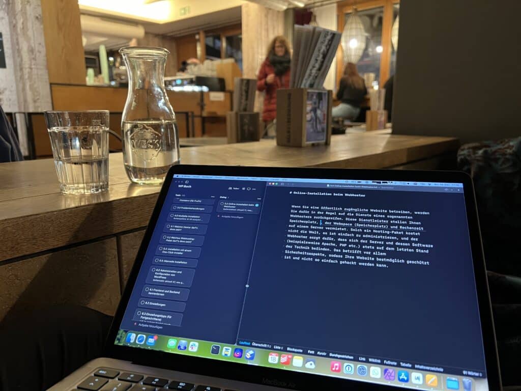 Photo of a MacBook screen in a cafe. On the screen we see a first paragraph of text (in German).