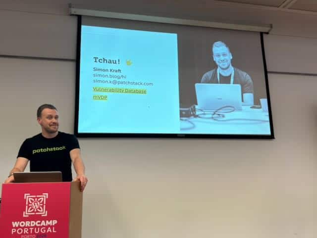 A man with a Patchstack Shirt (Simon) in front of a projector screen with a WordCamp Portugal Sign